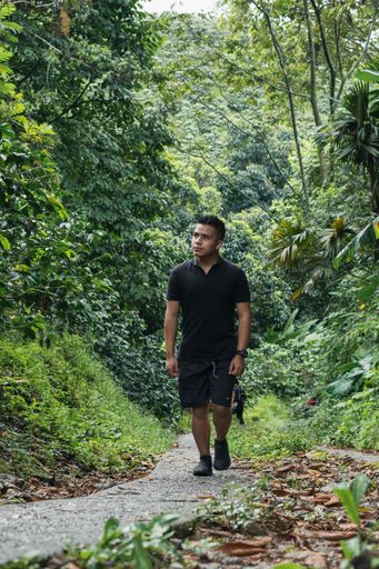 a vertical shot of man walking in forest park road