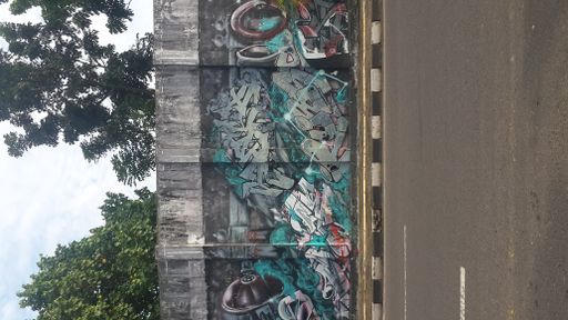A vertical shot of a wall covered in graffiti by the street.