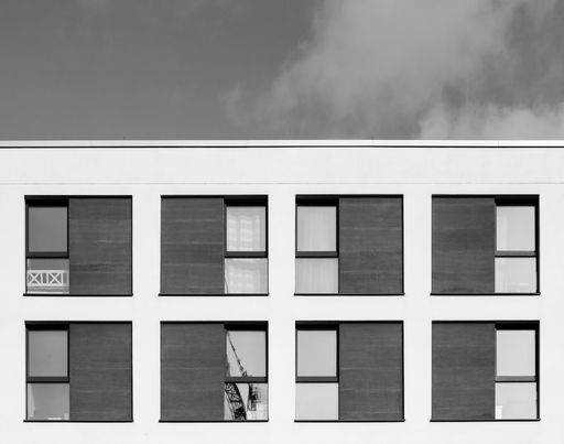 A grayscale shot of the windows in a modern building under cloudy sky