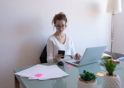 A selective focus shot of a young caucasian female with glasses working from home during COVID-19 pandemic