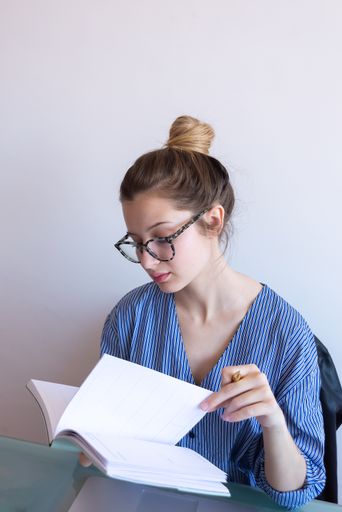 A selective focus shot of a young caucasian female with glasses working from home during COVID-19 pandemic
