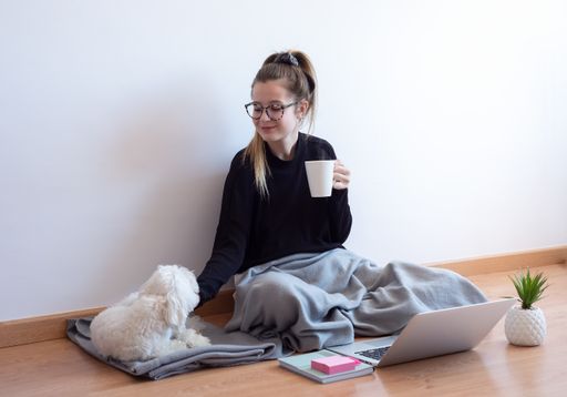 A selective focus shot of a young Caucasian female playing with a puppy at home during COVID-19 pandemic