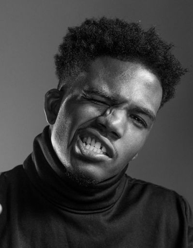 A vertical grayscale shot of an African American man making an angry face.