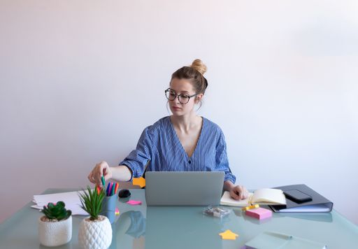 A selective focus shot of a young caucasian female with glasses working from home during COVID-19 pandemic