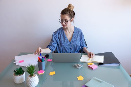 A selective focus shot of a young caucasian female with glasses working from home during COVID-19 pandemic