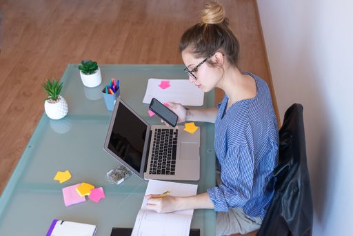 A selective focus shot of a young caucasian female with glasses working from home during COVID-19 pandemic