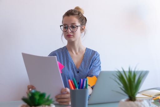 A selective focus shot of a young caucasian female with glasses working from home during COVID-19 pandemic