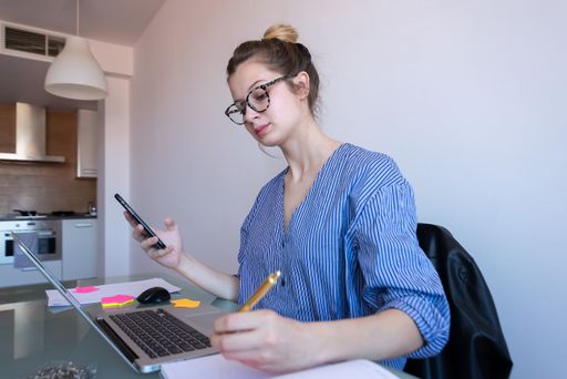 A selective focus shot of a young caucasian female with glasses working from home during COVID-19 pandemic