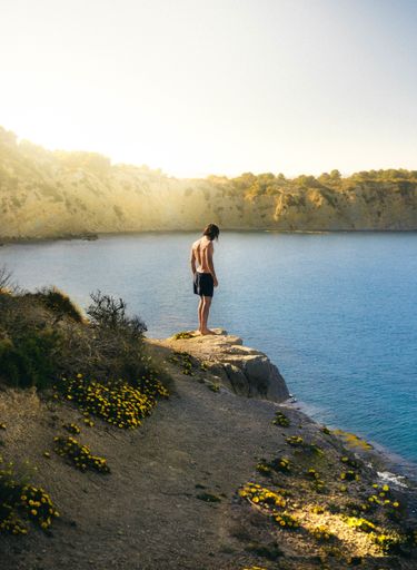 A vertical shot of a lonely male getting ready to jump into the lake on a sunny day