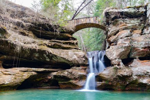 A photo of old rustic bridge and stones with waterfall in Hocking Hills State Park - Logan, OH