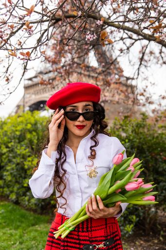 A portrait of a cute, stylish girl holding pink tulips on the background of Eiffel Tower