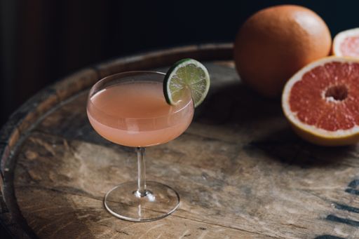 Hemingway daiquiri: grapefruit gin cocktail with lime wheel sitting on bourbon whiskey barrel