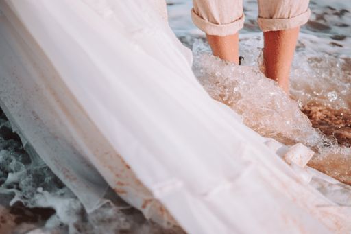 A closeup shot of people standing in the wavy sea with white fabric on the side