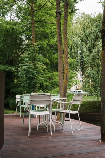 A vertical shot of empty tables and chairs restaurant's outdoor seating area
