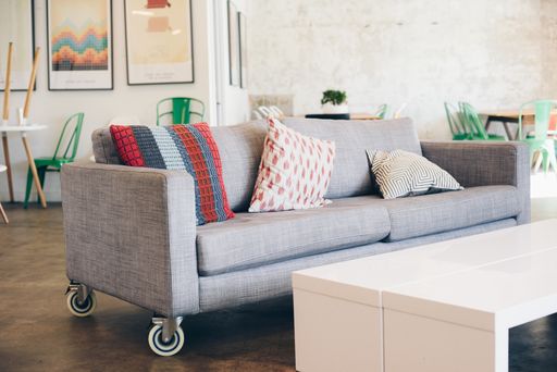 A beautiful shot of a gray couch with pillows near a white table