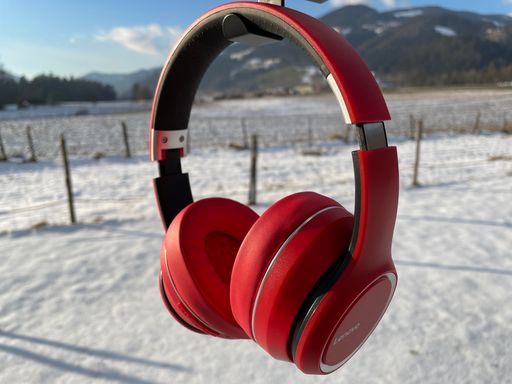 A closeup of the vibrant red Lenovo wireless headset with the snowy ground blurred in the background