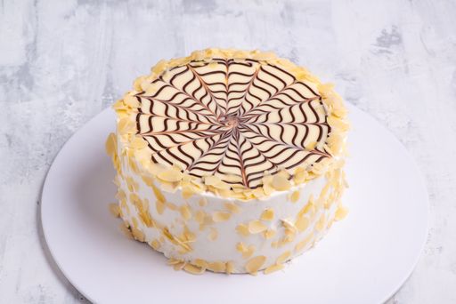 A cake made with layers of puff pastry filled with fresh cream and chocolate spider on a white plate on white marble surface