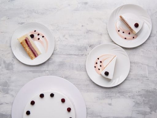A closeup shot of white-layered cake topped with fresh berries on white plates