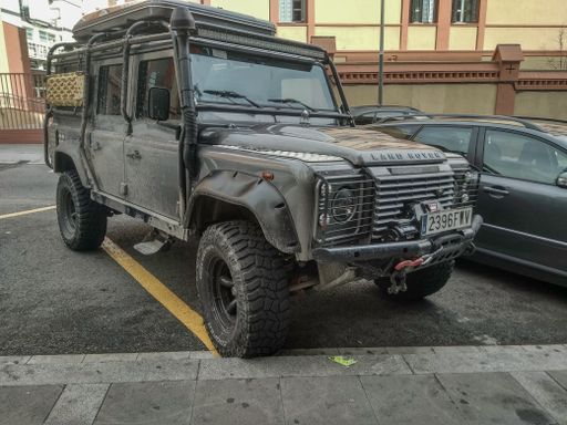 A classic 4x4 SUV offroad Land Rover Defender parked on the street
