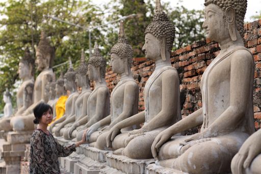 an Asian girl exploring row of Buddha statues at Wat Yai Chai Mongkhon temple in Ayutthaya, Thailan