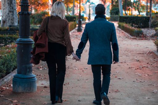 A back view of the lovely couple holding hands walking in the park