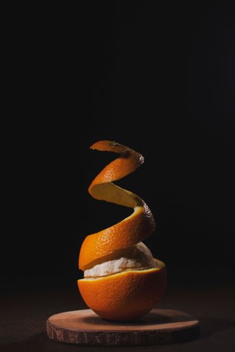 A vertical shot of orange peel floating in the air isolated on a black background