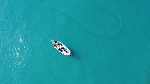 A top shot of a small boat in the clear blue sea. Perfect for wallpaper.