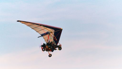 two people flying microlight in a summer sunset