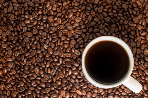 A top view of cup of coffee in background of coffee beans