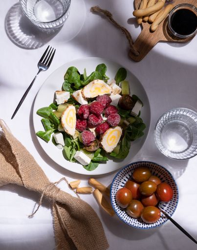 A top view of breakfast table with raspberries and rolls salad, churros and little tomatoes