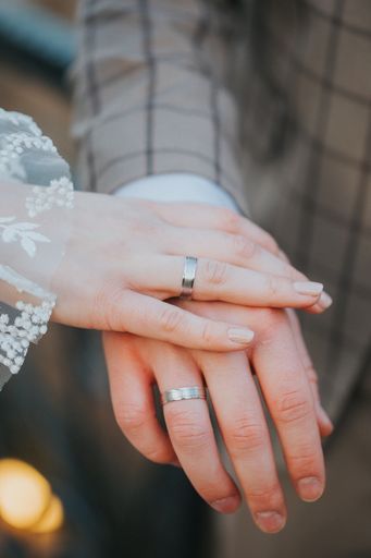 A vertical shot of a just married couple's hands
