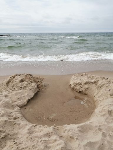 A vertical shot of a small bunker for the water made of sand at the beach