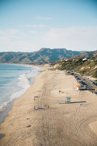 An aerial view of Zuma Beach and mountains against blue sky on a sunny day in Malibu, California, United States