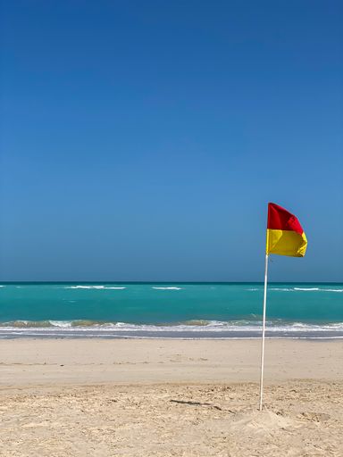 A lifeguard flag in the wind against the Arabian Sea