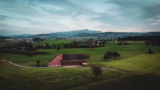 A beautiful view of a green landscape with houses under the cloudy sky