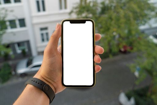 A man hand holding a smartphone similar to an iPhone X with a blank copy space outdoors