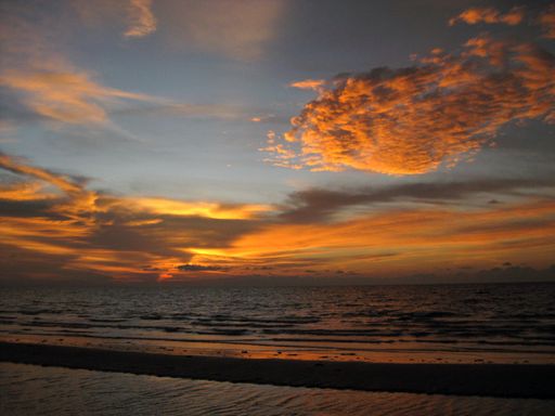 A breathtaking scenery of the sunset sky over gold-colored clouds reflected in the ocean