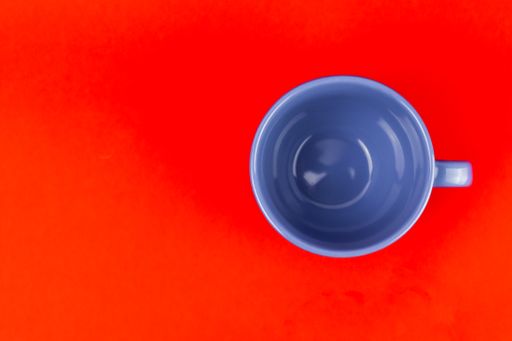 A top shot of a ceramic blue teacup on a red background.