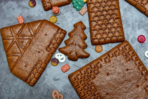 A top view of gingerbread house parts and decorations on a gray background