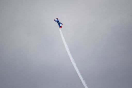 A low angle shot of a blue orange jet flying in a foggy sky for a sport jet show