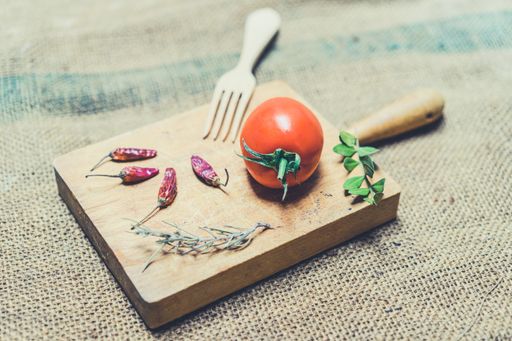 A high angle shot of a wooden board with tomato and ingredients and a fork