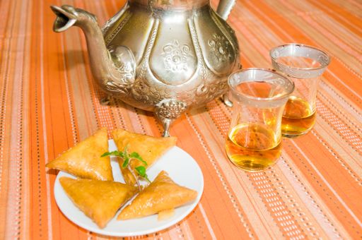 A high angle shot of cups of tea and freshly baked biscuits on an orange tablecloth