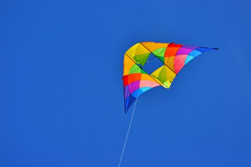 A closeup of a colorful kite isolated on a blue sky background