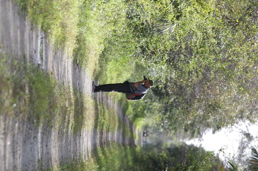 A vertical shot of a photographer taking pictures on a narrow trail through trees