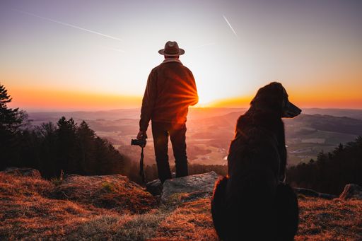 A dog and photographer with a camera enjoying a beautiful view during sunset