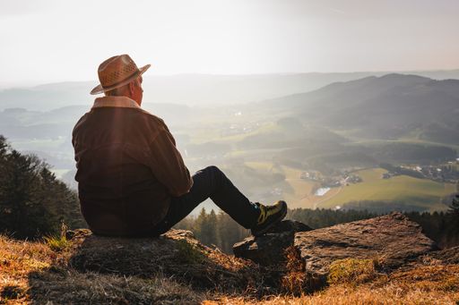 A man with a hat relaxing in the mountains during the sunrise