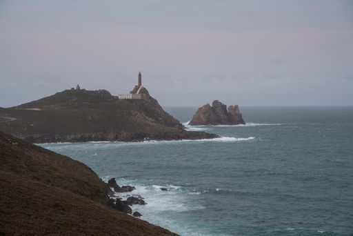 A landscape view of the Cabo Vilan lighthouse on the rocky hills on the west coast of Galicia, Spain