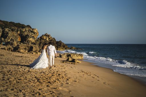 The bride and the groom walking at the sandy beach