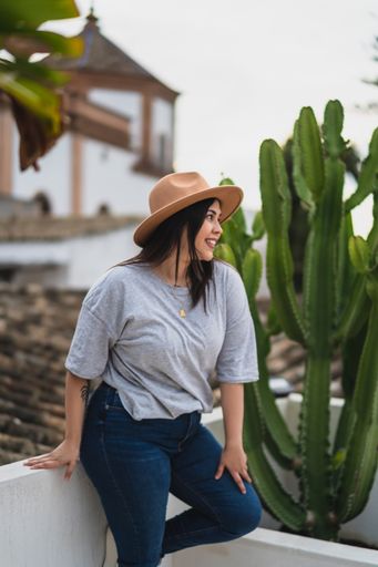A selective focus of a caucasian young woman with a hat posing on a rooftop