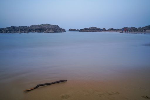 A view of a sea or ocean coast with gray rocks and people in the distance